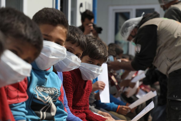Image: Displaced Syrian children and their parents attend a workshop organised by medical volunteers aimed at spreading awareness about COVID-19 coronavirus disease at a camp near the Syrian town of Atme close to the border with Turkey in Idlib province