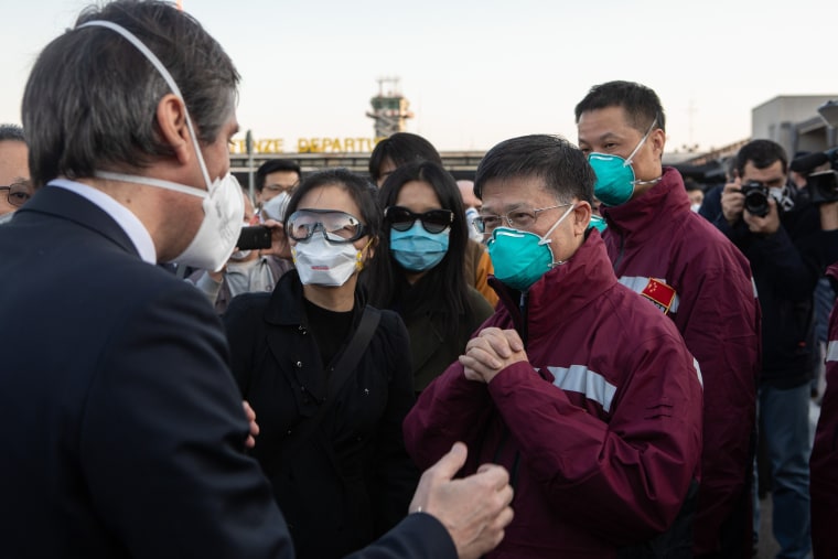 Image: Vice President of Lombardy Region Fabrizio Sala talks to a member of a Chinese Anti-Epidemic medical expert team pose for a photograph after landing at Milan - Malpensa airport