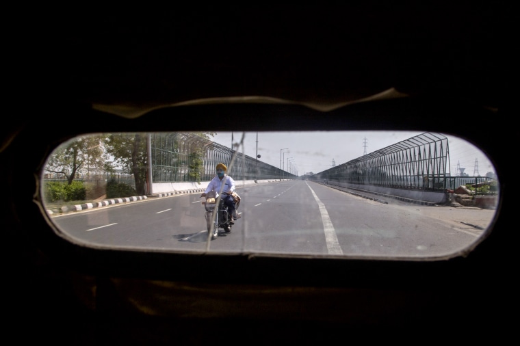 Image: A man wearing a mask rides a motorcycle on a deserted road in New Delhi, India, on March 22, 2020.