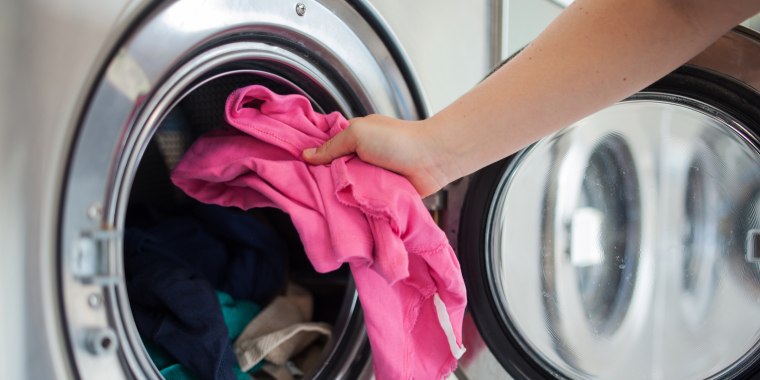 Woman putting shirt into washing machine