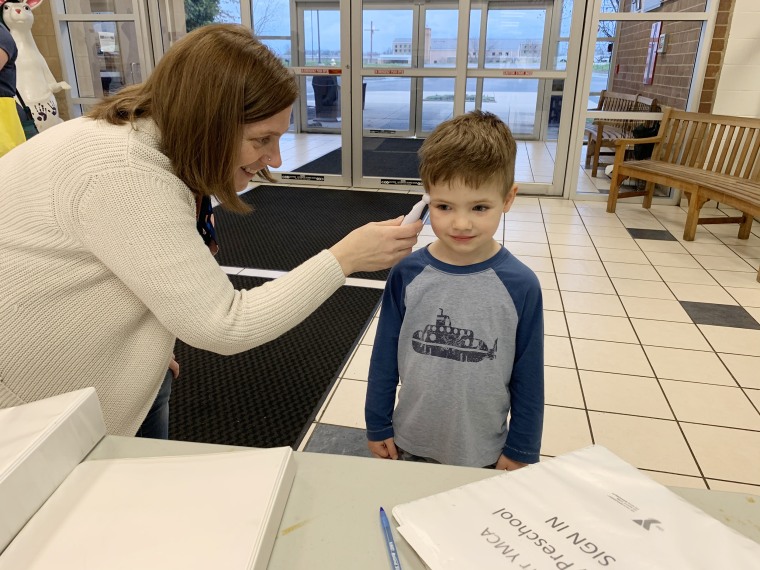 A boy has his temperature taken before he enters the YMCA of Greater Cincinnati, where child care is being provided for first responders and other essential workers.