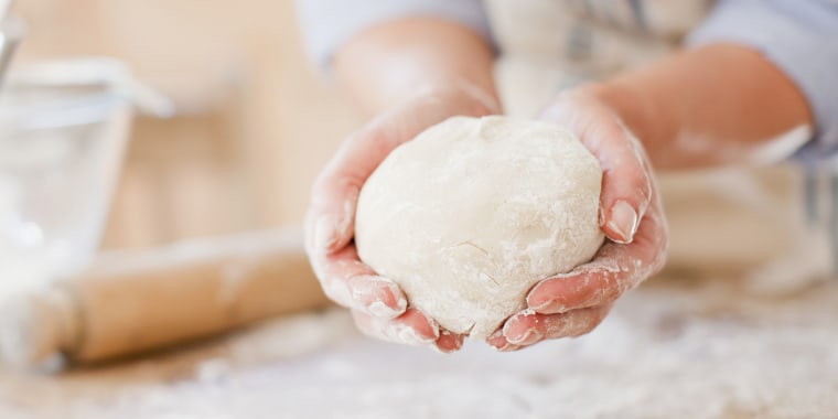 Woman holding ball of dough in kitchen