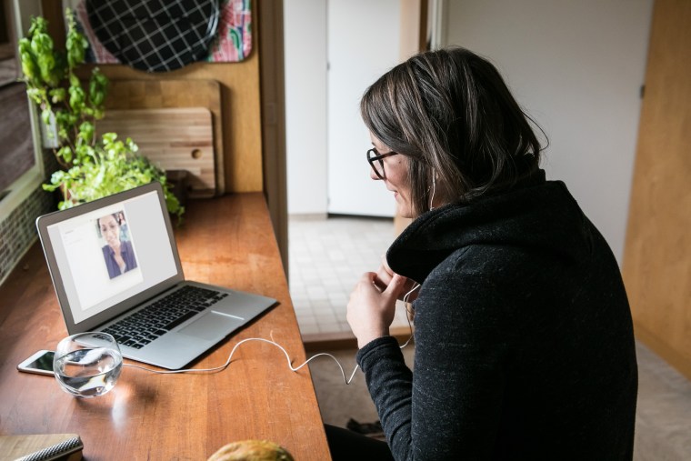 Side view of businesswoman video calling female colleague on laptop in home office