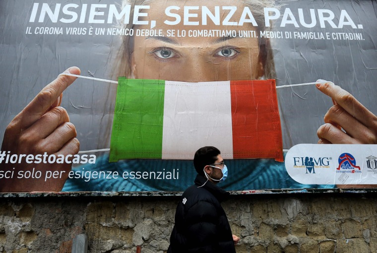 Image: A man walks past a large billboard raising awareness to the measures taken by the Italian government to fight against the spread of the COVID-19 (novel coronavirus) in the streets of Naples