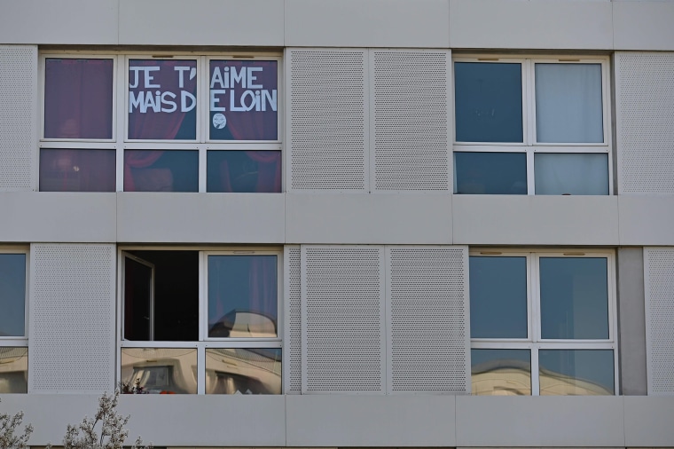 Image: A message reading "I love you but from far" is posted in the windows of an apartment building in Rennes on Tuesday.