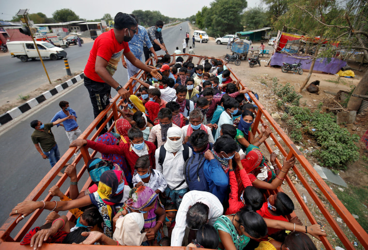 Image: Migrant workers and their families board a truck to return to their villages, in Ahmedabad