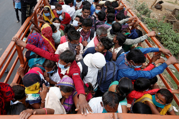Image: Migrant workers and their families board a truck to return to their villages, in Ahmedabad