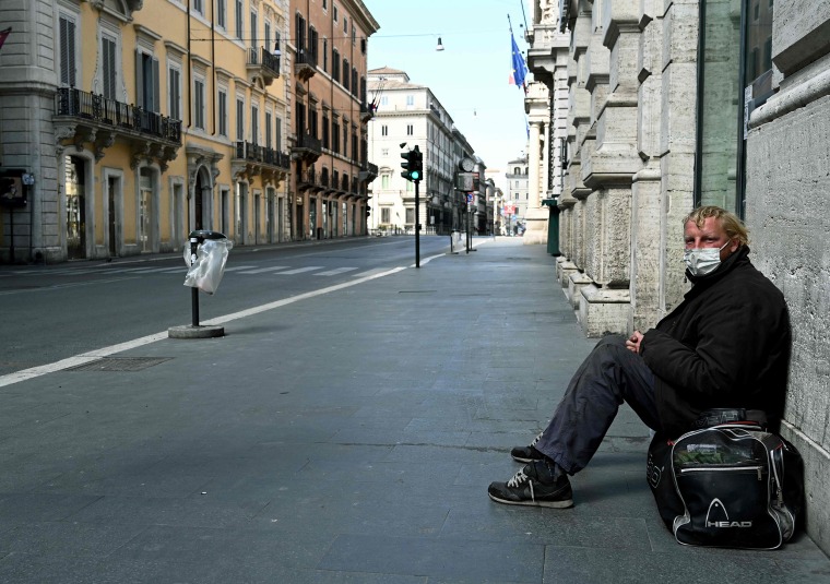 Image: A homeless man sits in Via del Corso in Rome