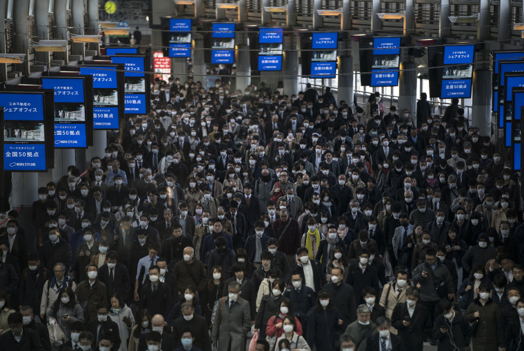 Image: Commuters in Japan wear face masks on Thursday.