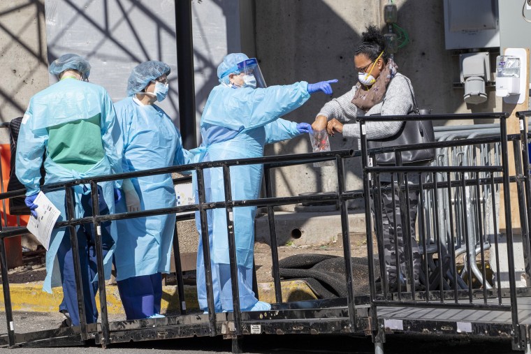 Image: A member of the Brooklyn Hospital Center helps a person who was just tested for COVID-19 put an object in a biohazard bag, Thursday, March 26, 2020, in New York.