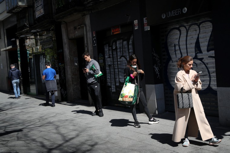 Image: People practice social distancing while waiting to enter a supermarket in Madrid on Sunday.