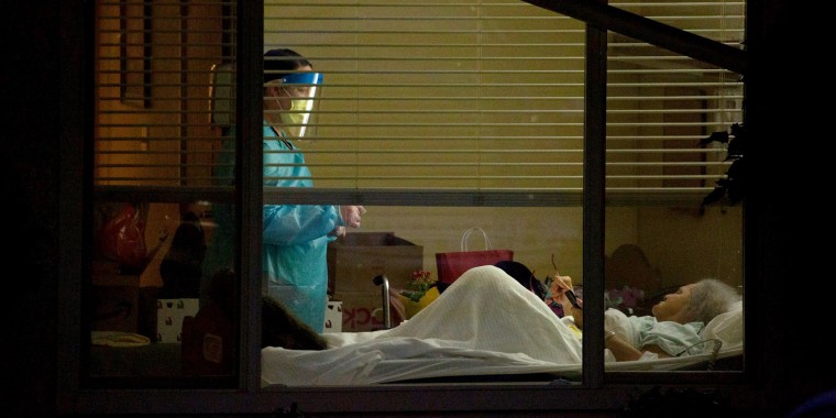 A healthcare worker attends to Susan Hailey, who tested positive for coronavirus, at the Life Care Center of Kirkland in Washington state on March 13, 2020.