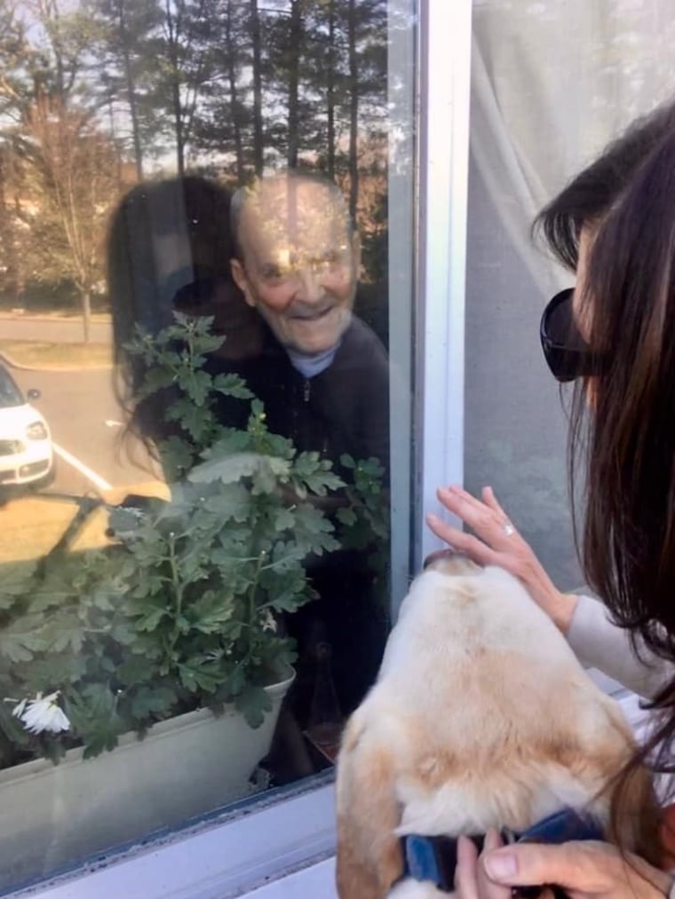 A man smiles from a window at his daughter and her dog.