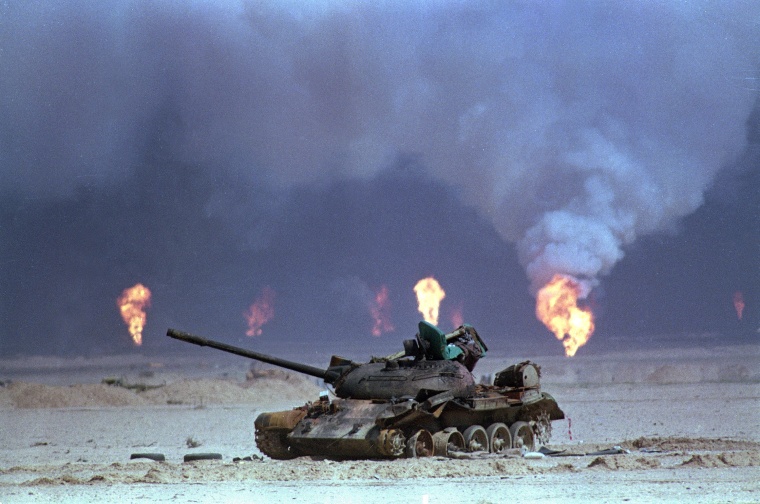 Image: A destroyed Iraqi tank rests near a series of oil well fires