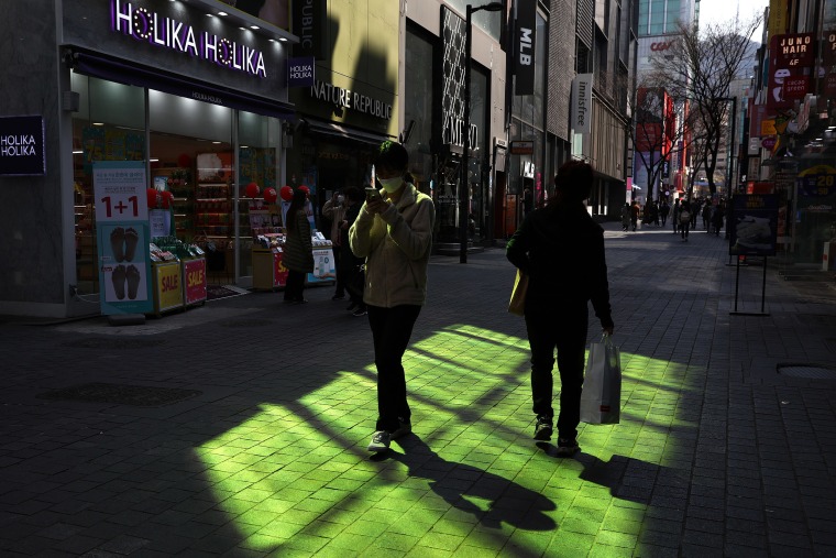 Image: A South Korean woman wears a mask while walking along the street in Seoul on Monday.