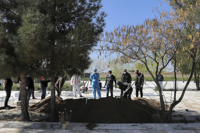 Image: People wearing protective clothing attend a funeral of a victim who died from the coronavirus at a cemetery outside Tehran, Iran on Monday.