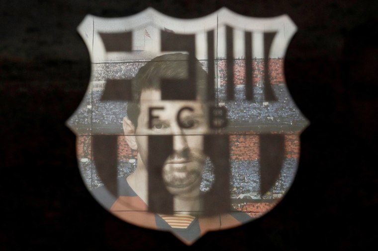 Image: A picture of soccer star Lionel Messi is reflected in the Barcelona soccer team's emblem outside the club's Camp Nou stadium before a match on March 7.