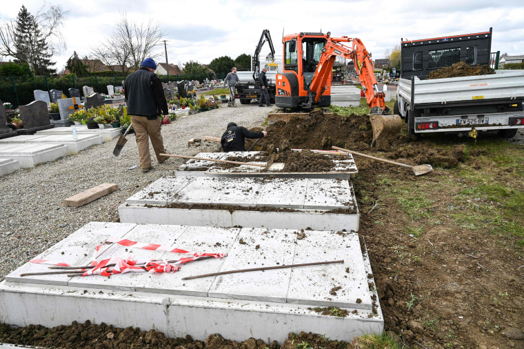 Image: Employees of a funeral company install 15 new burial vaults in a cemetery near Bethune, France on Monday.