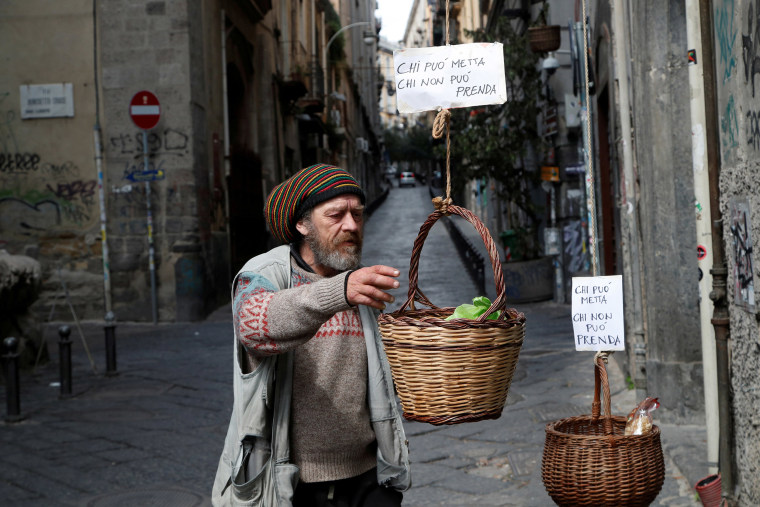 Image: A man reaches into a basket where people can donate or take food in Naples on Monday as Italy struggles to contain the spread of the coronavirus.