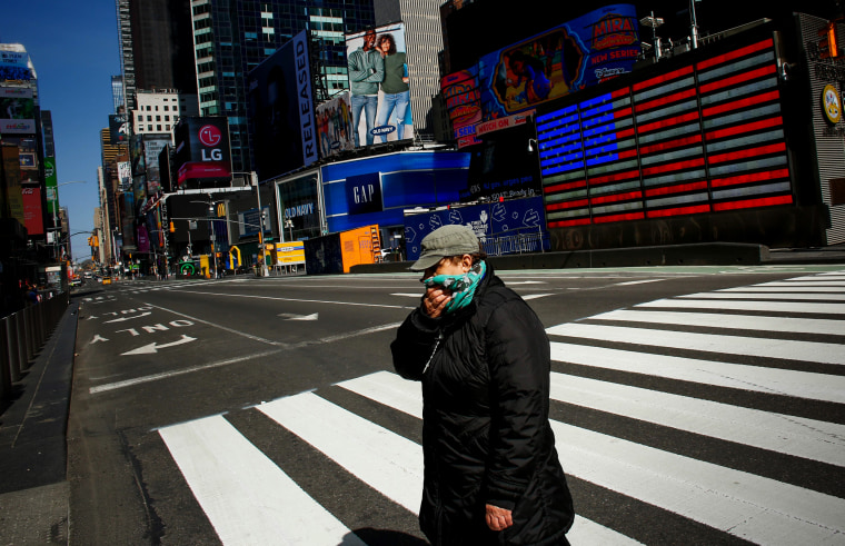Image: A woman crosses through Times Square as she covers her face on March 22, 2020.