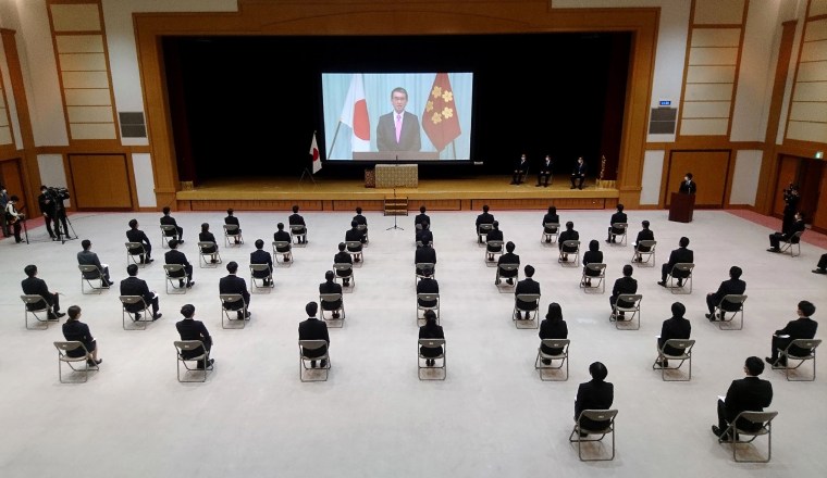 Image: New employees of Japan's Defense Ministry sit on chairs spaced apart for social distancing as they watch a video message of Defense Minister Taro Kono during a ceremony in Tokyo on Wednesday.