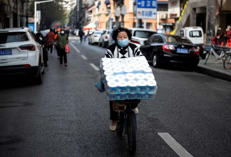 Image: A woman wearing a face mask pedals along a street in Wuhan, in China's central Hubei province