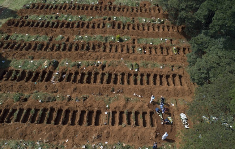 Image: Cemetery workers in protective clothing complete a burial at the Vila Formosa cemetery in Sao Paulo, Brazil on Wednesday.