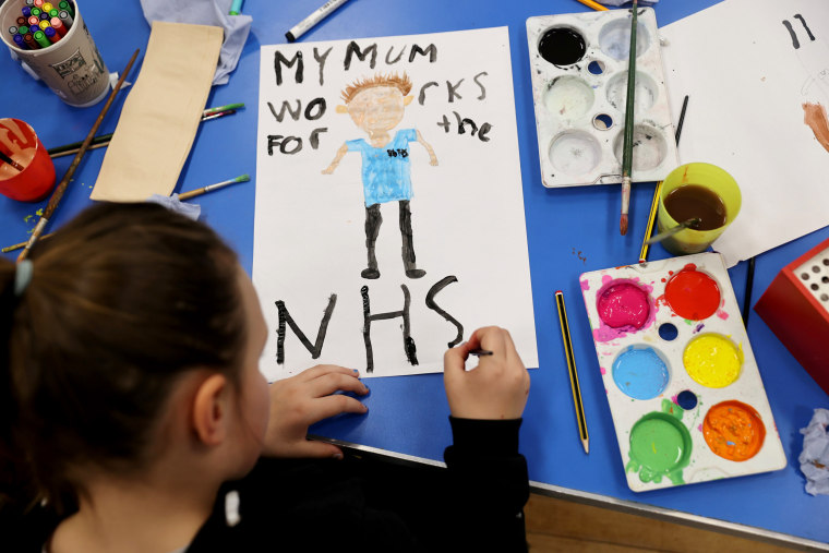 Image: A child at Westlands Primary School paints a poster in support of the NHS in Newcastle-under-Lyme, England, on April 2, 2020.