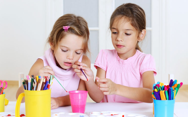 Two young girls painting together.