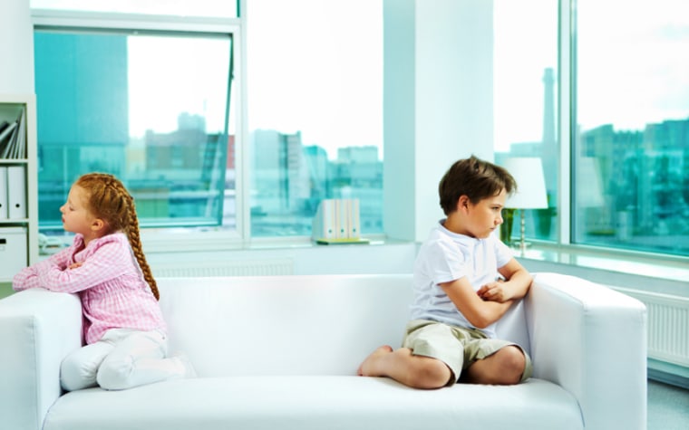 Young children argue on a couch.