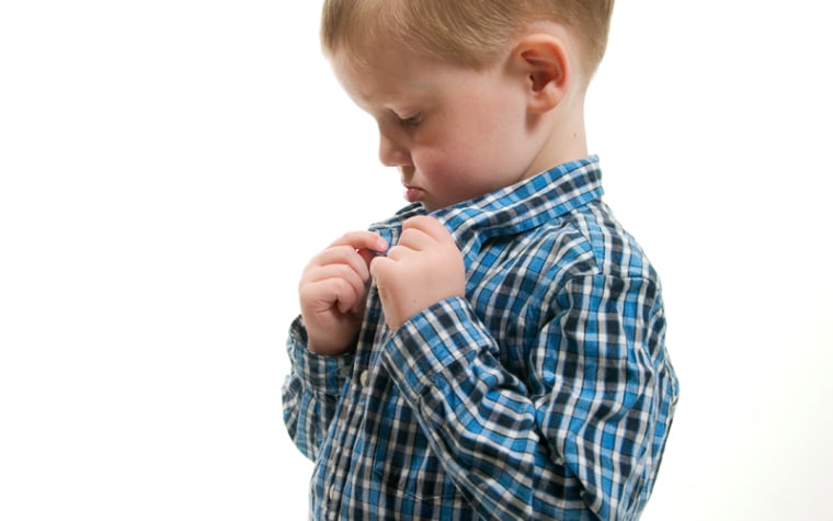 Young boy buttons shirt collar.