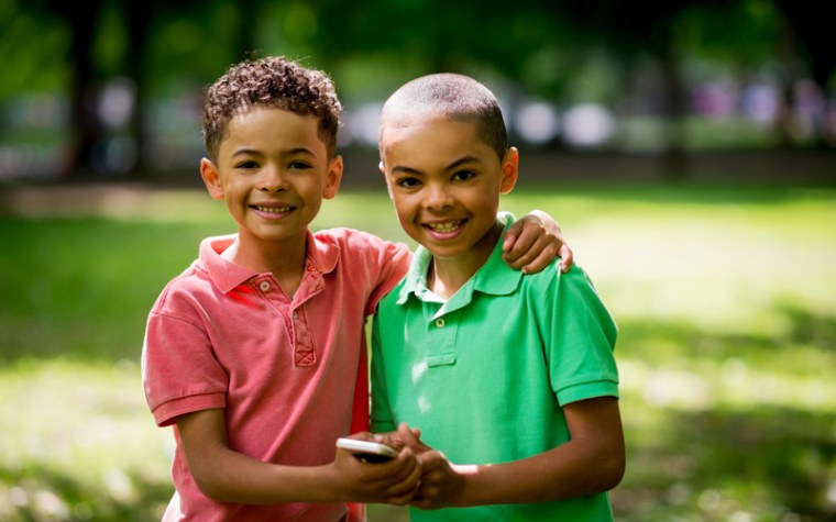 Two young boys smile outside.