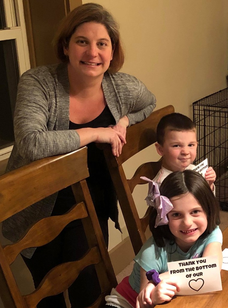Liz Bortnyik and her kids pose for a photo with the notes they've been sending people like health care workers.
