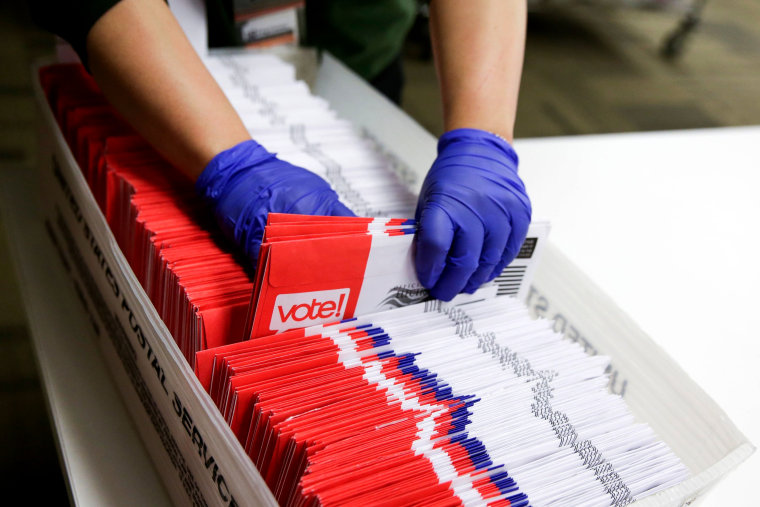 Image: A poll worker sorts vote-by-mail ballots in Renton, Wash., on March 10, 2020.