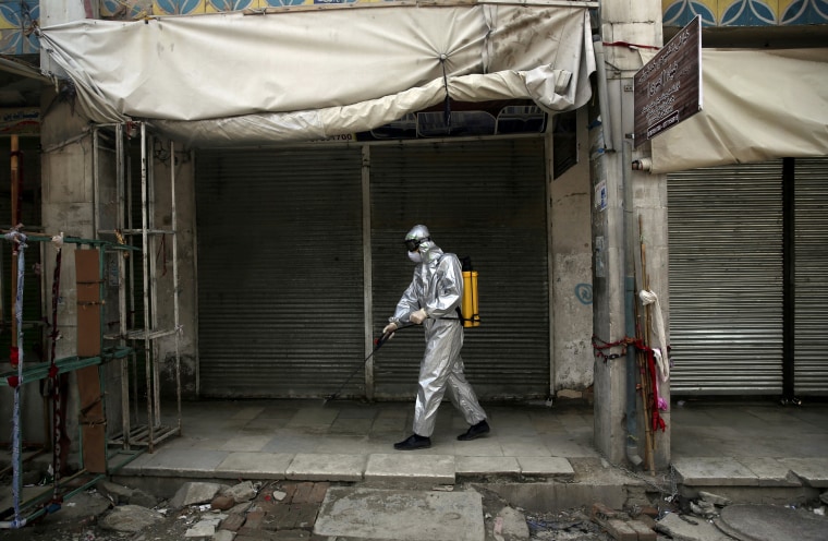 Image: Volunteers spray disinfectant on storefronts 