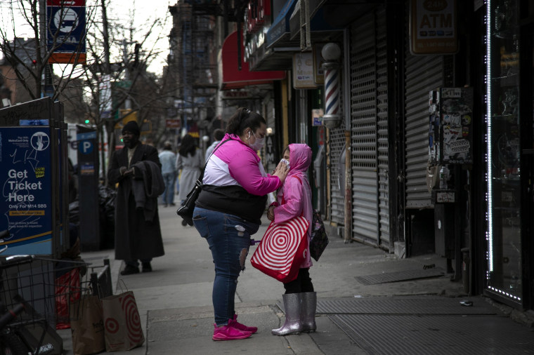 Image: A woman adjusts the face mask of a child in the East Village neighborhood of New York on March 19, 2020.