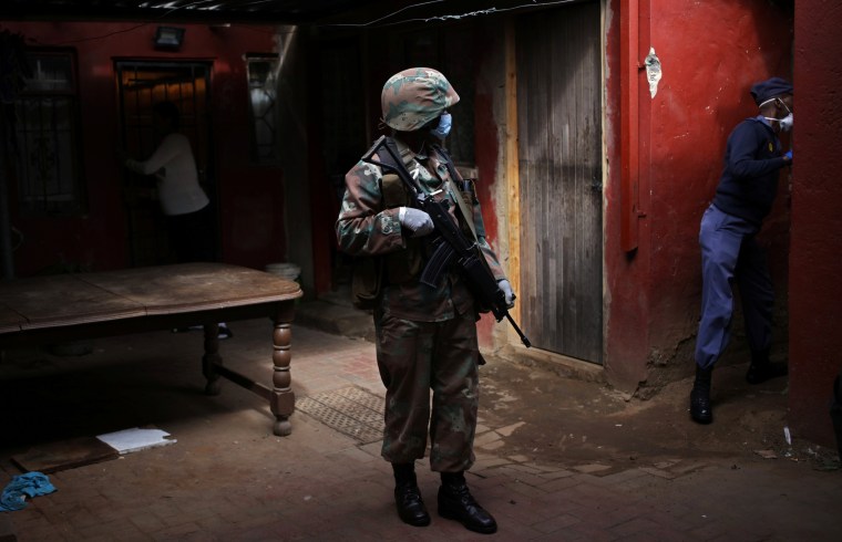 Image: A Soldier and a member of the South African police service search a house