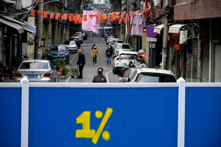 Image: People wearing face masks walk inside a barricaded residential compound in Wuhan, China, on Tuesday.