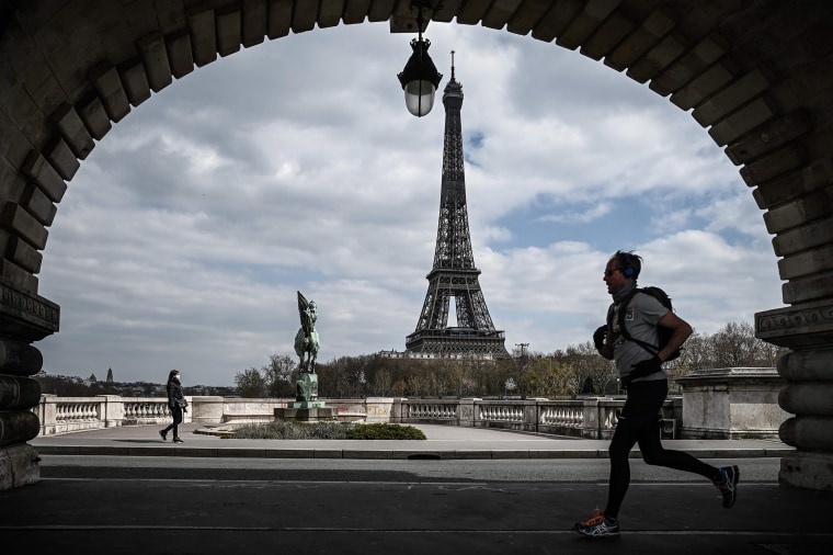 Image: A man jogs on a bridge in front of the Eiffel Tower in Paris on Thursday.