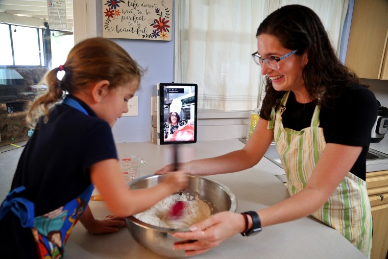 Image: Sarah Cowart, 6, helps her mother, Hana Cowart, mix dough to make matzo while watching a YouTube live video by Maureen Seehan, a director of learning at Congregation B'nai Israel of St. Petersburg, Fla., on March 31, 2020.