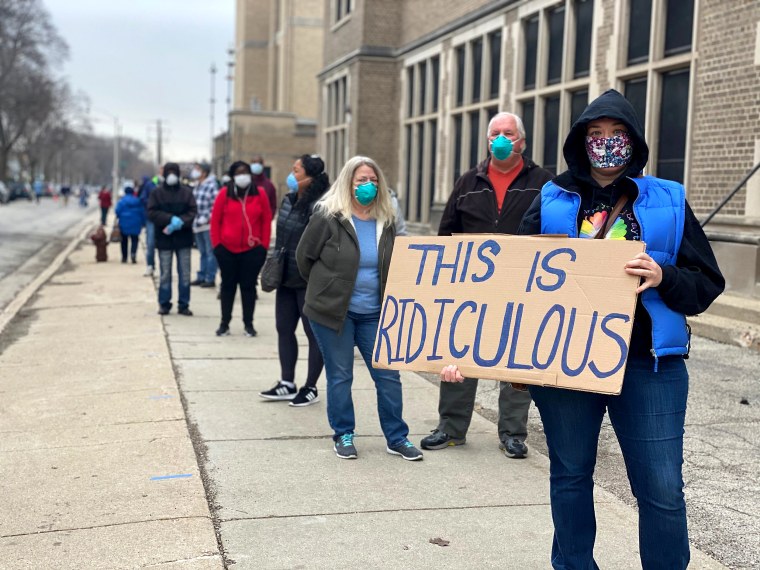 Apr 7, 2020; Milwaukee, Wisconsin, USA; Milwaukee resident Jennifer Taff holds a sign as she waits in line to vote at Washington