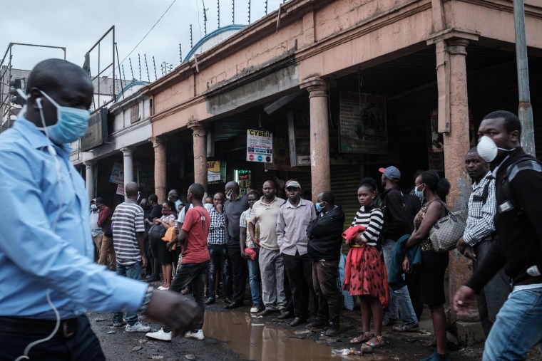Image: People wait in a line for a bus to go back to their homes before the night curfew starts in downtown Nairobi, Kenya