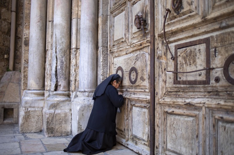 A nun prays in front of the closed door of the Church of the Holy Sepulchre in Jerusalem