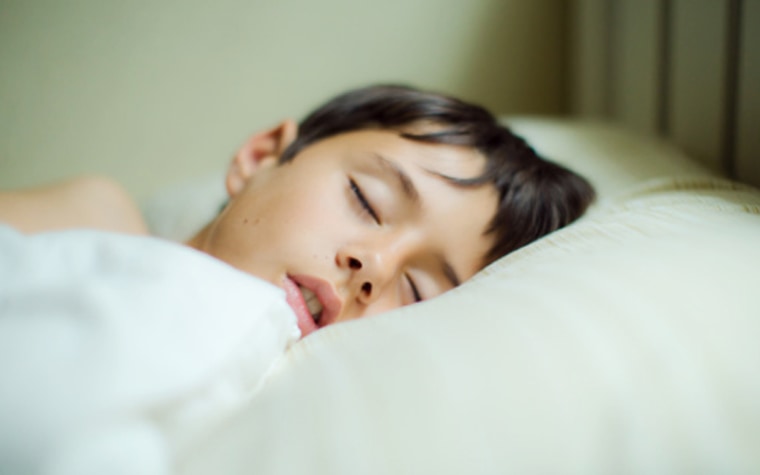 Little boy sleeping in bed with white sheets