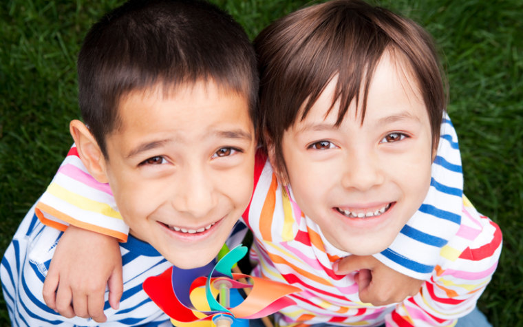 Sibling wrap arms around each other with windmill in hand