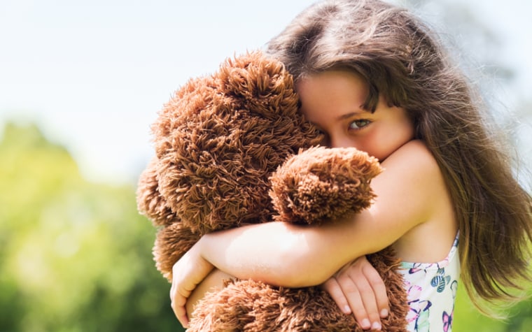 Young girl hugs stuffed animal outside