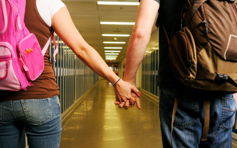 Middle school couple holding hangs in empty school hallway