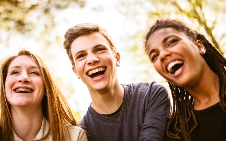 Group of three teens smiling and laughing together at school