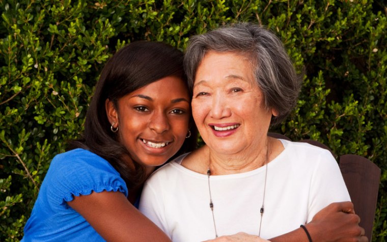 Teen hugging elderly woman in white top