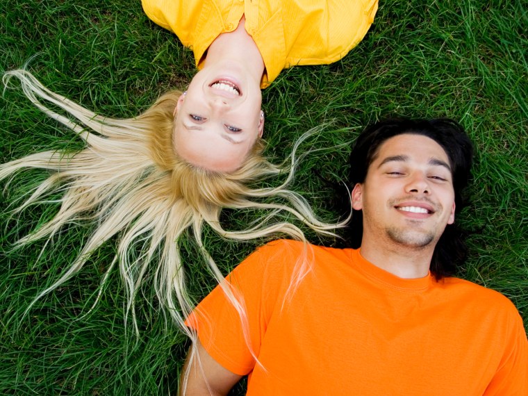 A teen boy and girl lay on the grass